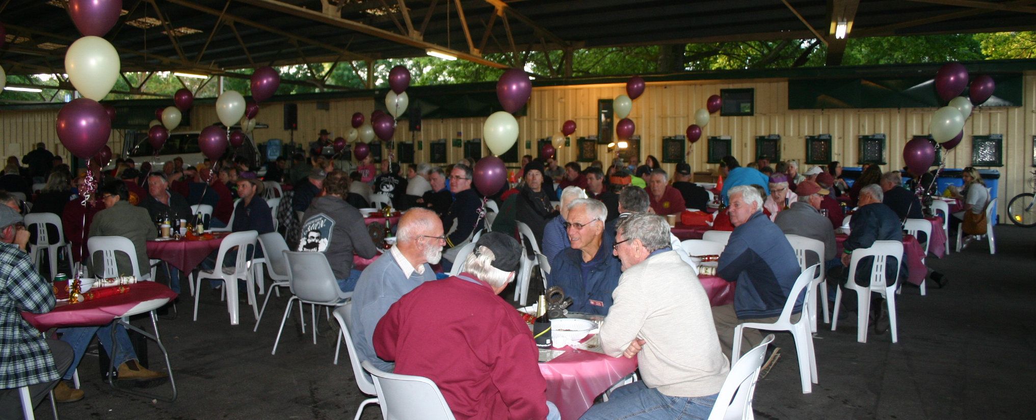 HCVCA Memebrs sitting around having a spit roast meal in the under cover area at Yarra Glen Racecourse.